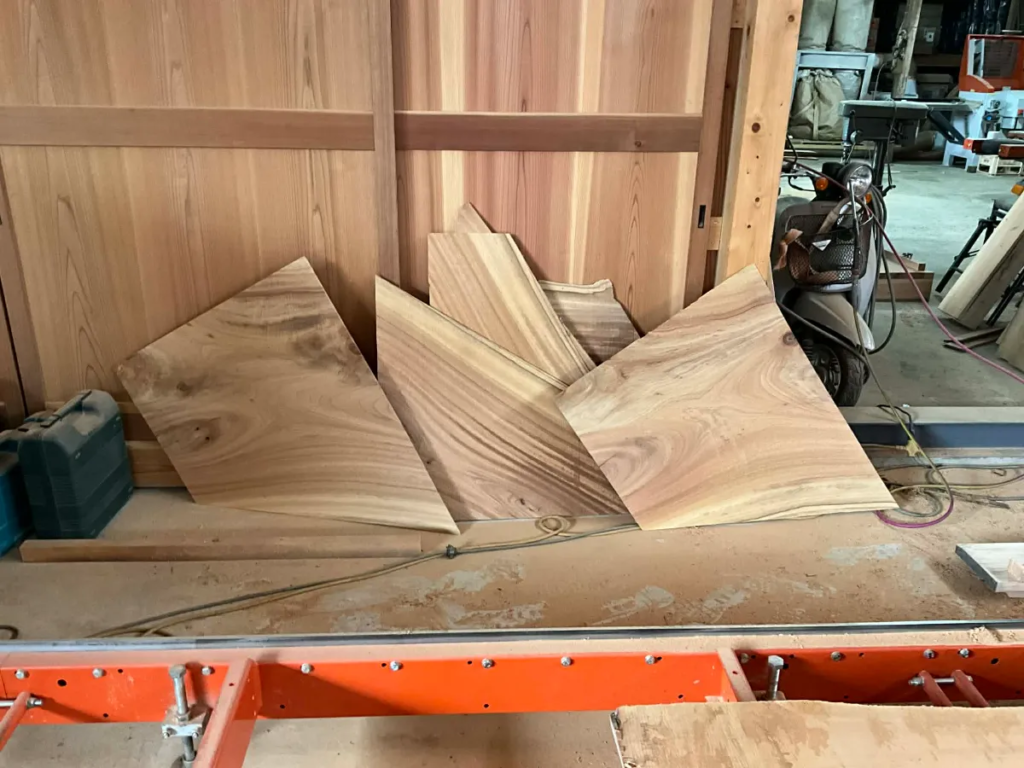 image - NO1製材機ウッドマイザー正規販売代理店│ウッドマイザージャパン MSco.,LTD. Stack of plywood panels leaning against a wooden wall in a woodworking shop with tools in the background.