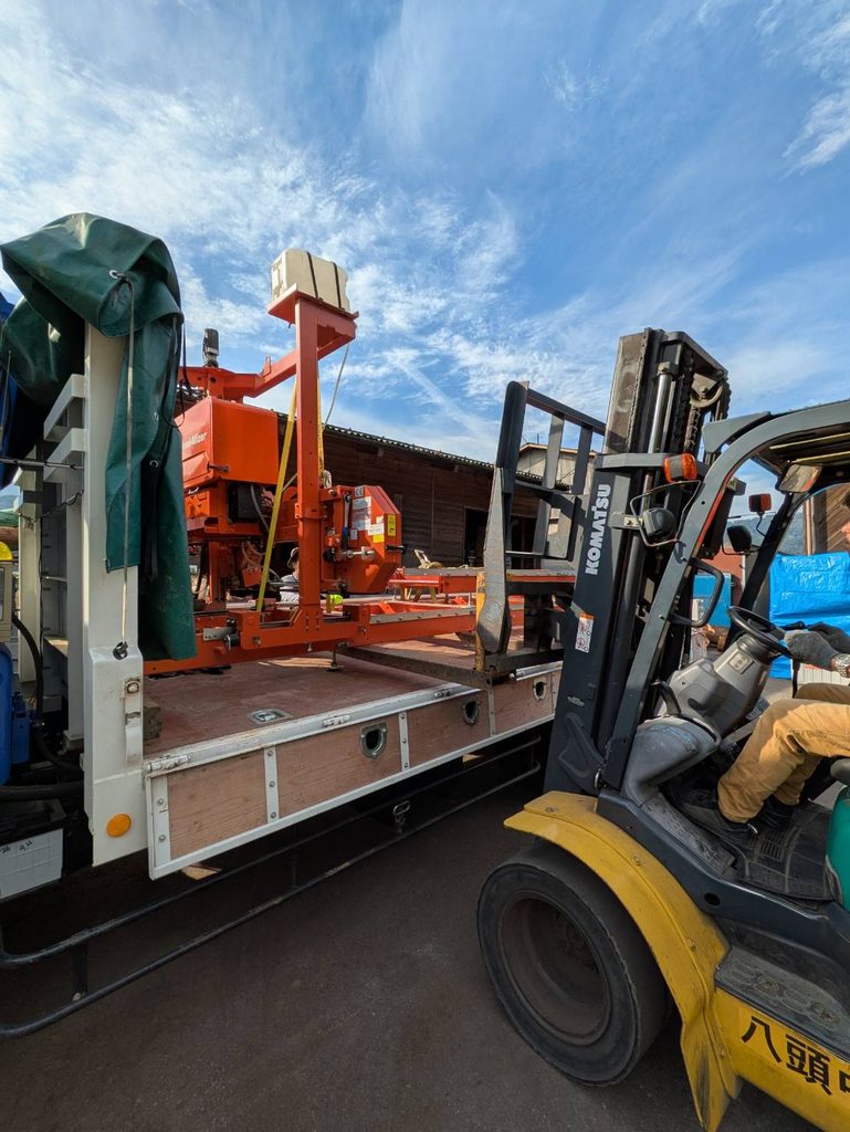 八頭中央森林組合のフォークリフトでトラックの荷台からウッドマイザー小型製材機LT15を積み下ろす様子